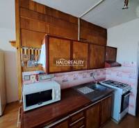 Nappali egy háromszobás lakásban kanapékkal, fa dekor padlóval és nagy ablakokkal.