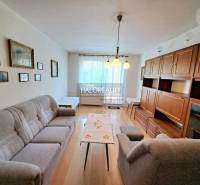 Nappali világítással, fa dekor padlóval és bútorokkal egy háromszobás lakásban.