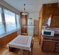 Nappali egy háromszobás lakásban, fa mintázatú padlóval, ülőgarnitúrával és fali dekorációkkal.