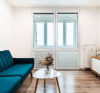 Nappali egy kétszobás lakásban kanapéval, televízióval és fa dekorációjú padlóval.