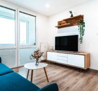 Nappali egy kétszobás lakásban kanapéval, televízióval és fa dekorációjú padlóval.