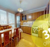 Konyha egy kétszobás lakásban világos fa dekorral és étkezőasztallal.