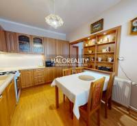 Konyha egy kétszobás lakásban étkezőasztallal és fa dekorációjú padlóval.