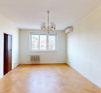 Nappali egy háromszobás lakásban csillárral és fa dekorációjú padlóval.