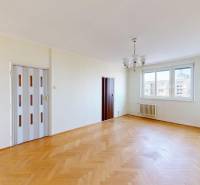 Nappali egy háromszobás lakásban nagy ablakokkal és fa dekorációjú padlóval.