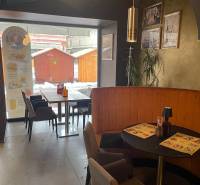 Vendéglátóhely kávézó jellegű ülőhelyekkel, falakon dekorációkkal és kilátással a kinti fa bódékra.