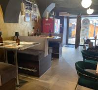 Vendéglátóhely belső tér kényelmes ülőhelyekkel és dekoratív lámpákkal.