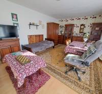 Szoba családi házban bútorokkal, fa dekoros padlóval és dekoratív szőnyegekkel.