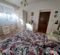 Hálószoba családi házban ággyal, ruhásszekrénnyel és dekoratív szőnyeggel.