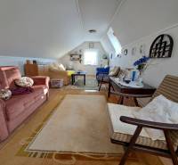 Családi ház tetőtéri nappalija kinyitható kanapéval és dekoratív kiegészítőkkel.