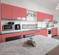 Konyha egy családi házban rózsaszín szekrényekkel és fehér asztallal.