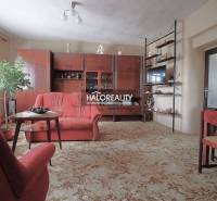 Nappali családi házban fotelekkel, vitrinnel és szőnyeggel.