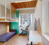 Gyerekszoba ággyal, íróasztallal, szőnyeggel, fa mintázatú padlóval és kerékpárral.