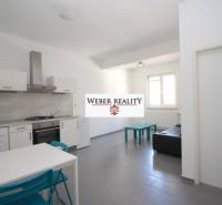 Nappali egy kétszobás lakásban konyhasarokkal, egyszerű berendezéssel és ablakkal.