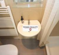 Fürdőszoba egy kétszobás lakásban zuhanyzóval és kerámia mosdóval.