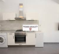 Konyha egy 2 szobás lakásban háztartási gépekkel és falra szerelt televízióval.