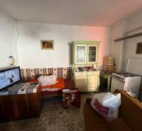 Szoba kanapéval, konyhapulttal, tűzhellyel és televízióval egy családi házban.