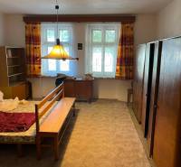 Hálószoba családi házban szőnyegpadlóval és világos színű bútorokkal.