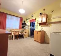 Konyha családi házban fa dekorációval, világos falakkal, asztal székekkel.