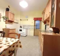 Családi ház konyhája étkezőasztallal és fa szekrényekkel.