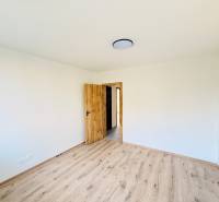 Szoba egy háromszobás lakásban fehér falakkal és fa dekorációjú padlóval.