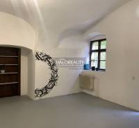 Egy fehér falú, ablakkal, fali dekorációval és fa polccal rendelkező iroda belső tere.