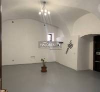 Irodák belső tere fehér falakkal, boltíves mennyezettel és cserepes növénnyel.