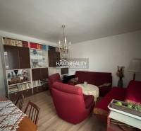 Nappali egy háromszobás lakásban fa dekor padlóval és piros fotelekkel.