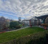 A Szepesújvár kertjei gondozott bokrokkal, gyepes területtel és fa pavilonnal.