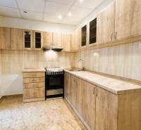 Konyha egy háromszobás lakásban fa dekorációjú szekrényekkel és csempével.