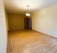 Nappali szoba fa dekor padlóval, csillárral és mintás fal egy háromszobás lakásban.