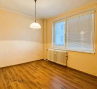 Szoba egy háromszobás lakásban fa dekor padlóval és nagy ablakkal.