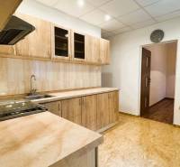 Konyha egy háromszobás lakásban, fa dekorációjú konyhabútorral és padlóval.