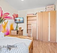 Hálószoba családi házban virágos tapétával, fa dekor padlóval és bútorokkal.