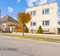 Családi házak Dunaszerdahelyen, fákkal szegélyezett utcák, rácsos kerítések, kék ég.