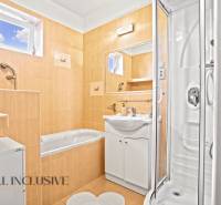 Fürdőszoba családi házban káddal, zuhanyzóval és tükörrel az okkersárga csempéken.