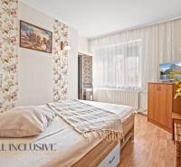 Hálószoba családi házban, ággyal, virágmintás tapétával és fa dekorációjú padlóval.