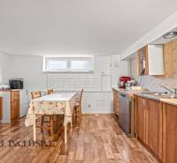 Konyha egy családi házban fa dekor padlóval, természetes szekrényekkel, világos asztallal.