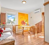 Családi ház napos dekorációval a falon, fa mintázatú padlóval és virágokkal teli vázával.