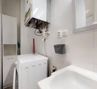 A háromszobás lakás fürdőszobája berendezésekkel, mosdóval és tükörrel a falon.