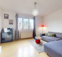 Nappali egy háromszobás lakásban kanapéval, asztallal és fa dekorációjú padlóval.