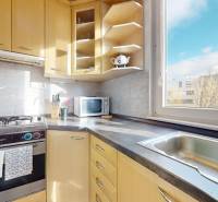 Konyha egy háromszobás lakásban fa szekrényekkel, gáz tűzhellyel és kilátással az ablakból.