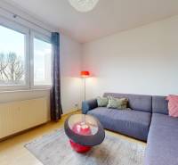 Nappali egy háromszobás lakásban nagy ablakokkal, kanapéval és asztallal.