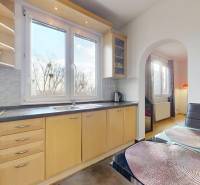 Konyha egy 3 szobás lakásban nagy ablakkal, világos bútorokkal és fa dekoros padlóval.