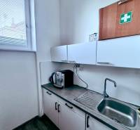 Irodai konyhasarok szekrényekkel, mosogatóval és kávéfőzővel.