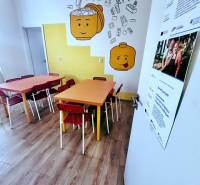 Gyereksarok színes asztalokkal, székekkel és fa dekorációjú padlóval az irodában.