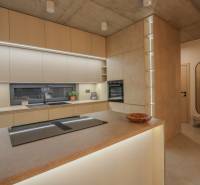 Konyha családi házban beépített készülékekkel, munkalapokkal és fa dekorációjú padlóval.