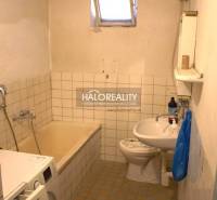 Fürdőszoba régebbi káddal, mosdóval és mosógéppel egy családi házban.