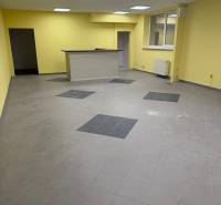 Sárga falak, szürke padló és fa pult az üzlethelyiségben.