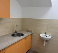 Konyhasarok üzlethelyiségben narancssárga szekrényekkel és mosogatóval.